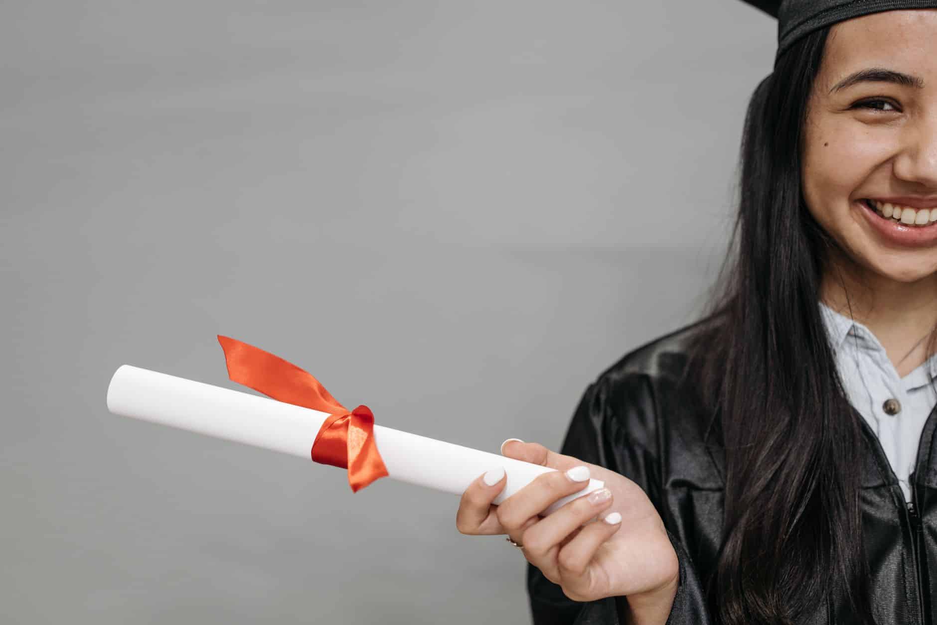 smiling woman in black graduation gown holding a diploma